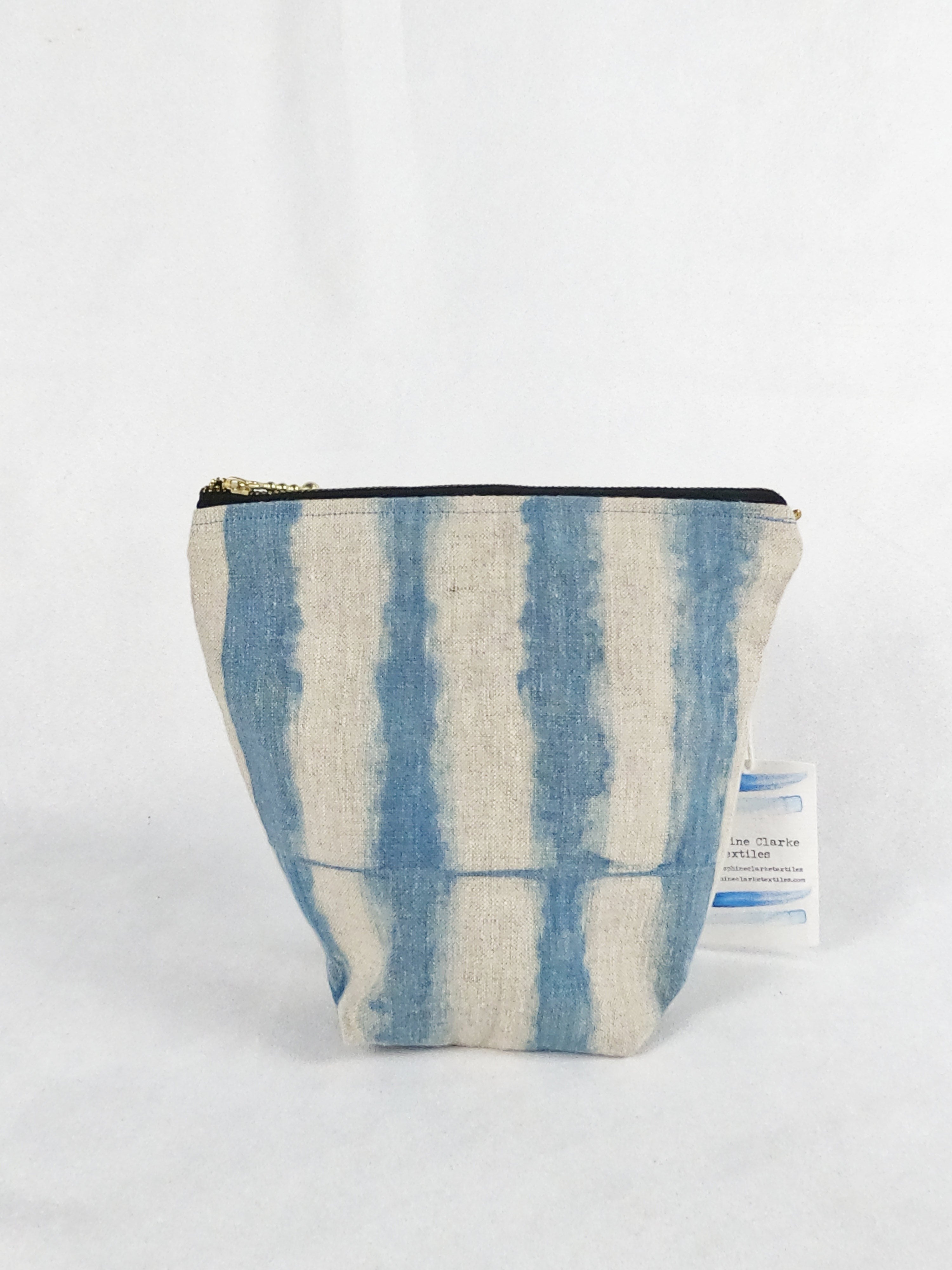 A blue and tan zipper pouch bag with a striped pattern. It is wide at the top and narrow at the bottom.