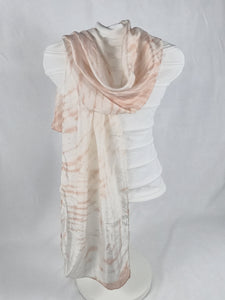 A silk scarf styled on a mannequin. It is white and peach in colour. It has a ripple like print.