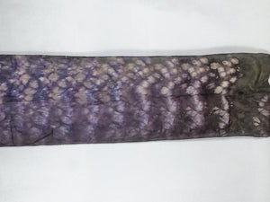 A silk scarf laid flat. It is dark purple and brown in colour.